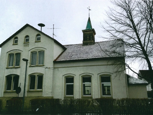 alte Schule Ehemaliges Schulgebäude mit Glockenturm, umgeben von kahlen Bäumen und Hecken im Winter.