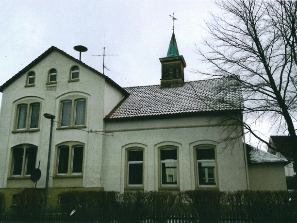 alte Schule Ehemaliges Schulgebäude mit Glockenturm, umgeben von kahlen Bäumen und Hecken im Winter.
