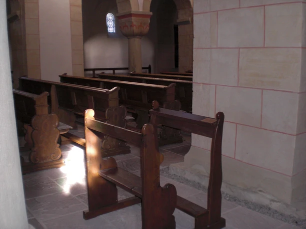 Scharfrichterbank Kilianskirche Kircheninnere mit dunklen Holzbänken, gedämpftes Licht durch ein rundes Kirchenfenster.