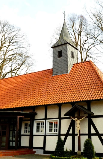 Kapelle Lippling Kapelle mit roten Dachziegeln und Fachwerk, umgeben von Bäumen, mit kleinem Kirchturm und Kreuz.