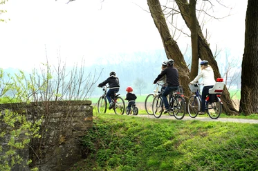 Radler am Boker Kanal Radfahrer, darunter ein Kind, fahren entlang eines grünen Weges am Ufer des Boker Kanals entlang.