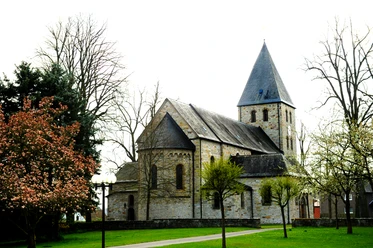 Kirche in Boke Historische Steinkirche mit Turm umgeben von blühenden Bäumen vor einem klaren Frühlingshimmel.