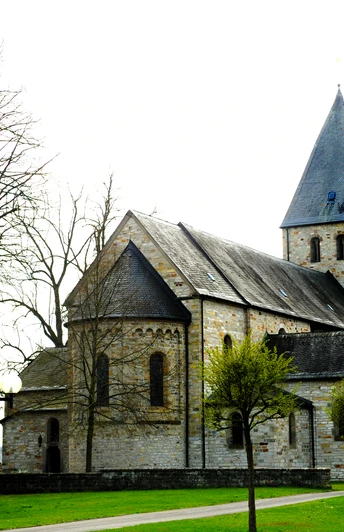 Kirche in Boke Historische Steinkirche mit Turm umgeben von blühenden Bäumen vor einem klaren Frühlingshimmel.