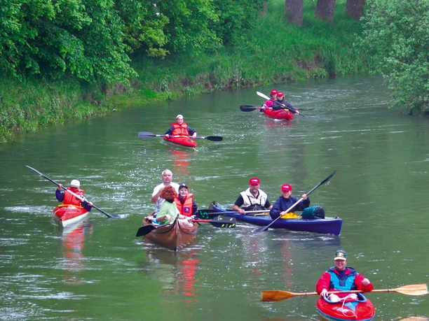 Kanufahrer auf der Lippe Kanufahrer paddeln auf einem grünen Fluss, umgeben von üppigen, bewaldeten Ufern.