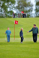 Swin-Golf Anlage in Westenholz Kinder und Erwachsener beim Swin-Golf auf grüner Anlage mit rotem Fähnchen der Bahn 9.