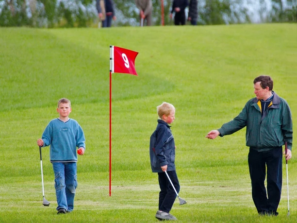 Swin-Golf Anlage in Westenholz Kinder und Erwachsener beim Swin-Golf auf grüner Anlage mit rotem Fähnchen der Bahn 9.