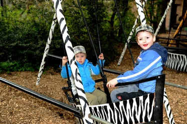 Kinder im Tierpark Nadermann Zwei Kinder schaukeln vergnügt auf einer Zebrastreifen-Schaukel im Tierpark Nadermann.