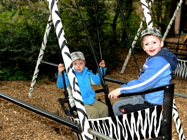 Kinder im Tierpark Nadermann Zwei Kinder schaukeln vergnügt auf einer Zebrastreifen-Schaukel im Tierpark Nadermann.