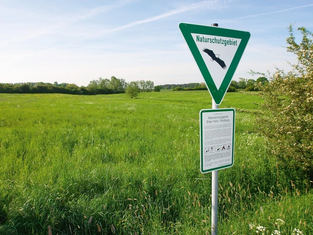 Naturschutzgebiet in Bentfeld Grüne Wiesen und ein Schild mit Hinweis auf ein Naturschutzgebiet unter blauem Himmel.