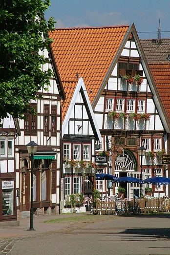 Fachwerkhäuser aus dem Mittelalter mit roten Ziegeldächern, Café mit Außenbestuhlung an der Straße.