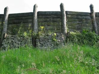 Wallanlage Nachbau Nachbau einer historischen Wallanlage aus Holz und Stein, umgeben von grüner Vegetation.