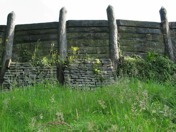 Wallanlage Nachbau Nachbau einer historischen Wallanlage aus Holz und Stein, umgeben von grüner Vegetation.