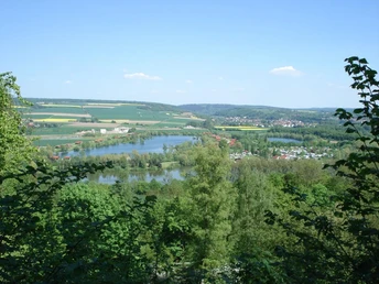 Blick über das grüne Wesertal mit Feldern, Hügeln, einem Fluss und umliegenden Waldgebieten.