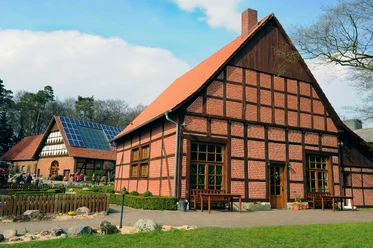 Seglings Hof Historischer Fachwerkhof mit rotem Backstein und Solarpanelen, umgeben von Rasen und Bäumen.