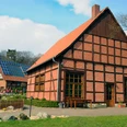 Seglings Hof Historischer Fachwerkhof mit rotem Backstein und Solarpanelen, umgeben von Rasen und Bäumen.