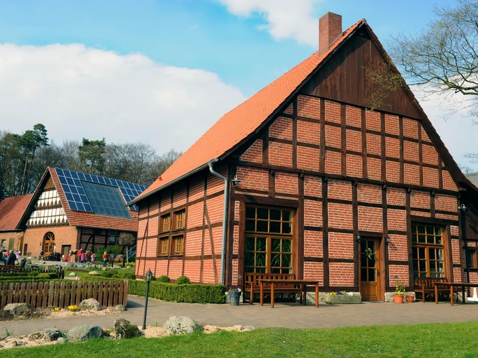 Seglings Hof Historischer Fachwerkhof mit rotem Backstein und Solarpanelen, umgeben von Rasen und Bäumen.