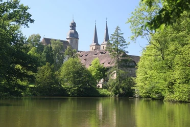 Abtei Marienmünster Abtei Marienmünster mit romanischer Architektur, umgeben von üppigem Grün und spiegelndem Teich.