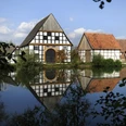 Der Dorfteich des LWL-Freilichtmuseums Detmold. Der Dorfteich im LWL-Freilichtmuseum Detmold spiegelt Fachwerkhäuser und bewölkten Himmel wider.