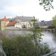 Wasserschloss Tatenhausen Historisches Wasserschloss reflektiert im ruhigen Weiher, umrahmt von grüner Vegetation und Bäumen.
