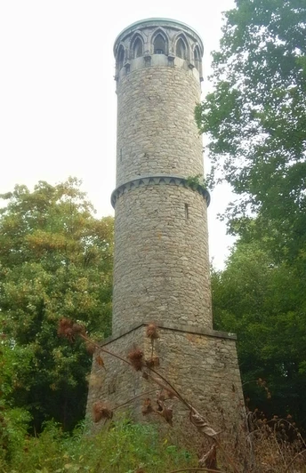 image Der runde, steinerne Aussichtsturm erhebt sich umgeben von dichtem, grünem Wald im Freien.