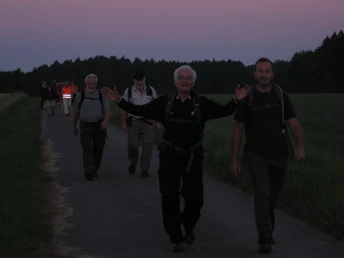 Den Alltag vergessen... Eine Gruppe älterer Wanderer genießt in der Abenddämmerung einen Spaziergang auf einem ländlichen Weg.