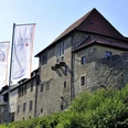 Historische Burg Sternberg mit markanten Steinfassaden und drei großen weißen Fahnen im Vordergrund.