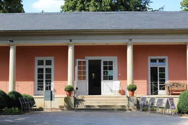 Romantik Bad Rehburg Geschichtsträchtiges Gebäude mit Säuleneingang, orangener Fassade und einladenden Stühlen draussen.
