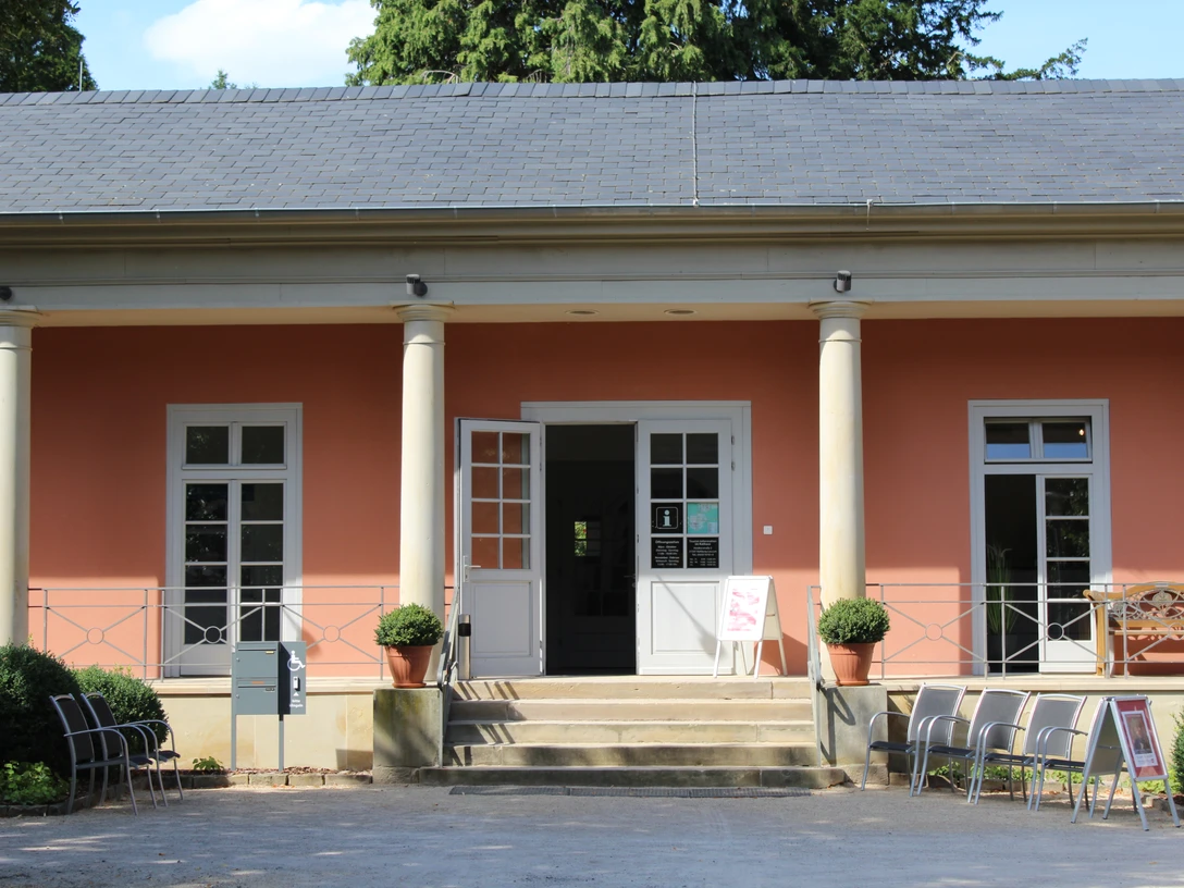 Romantik Bad Rehburg Geschichtsträchtiges Gebäude mit Säuleneingang, orangener Fassade und einladenden Stühlen draussen.