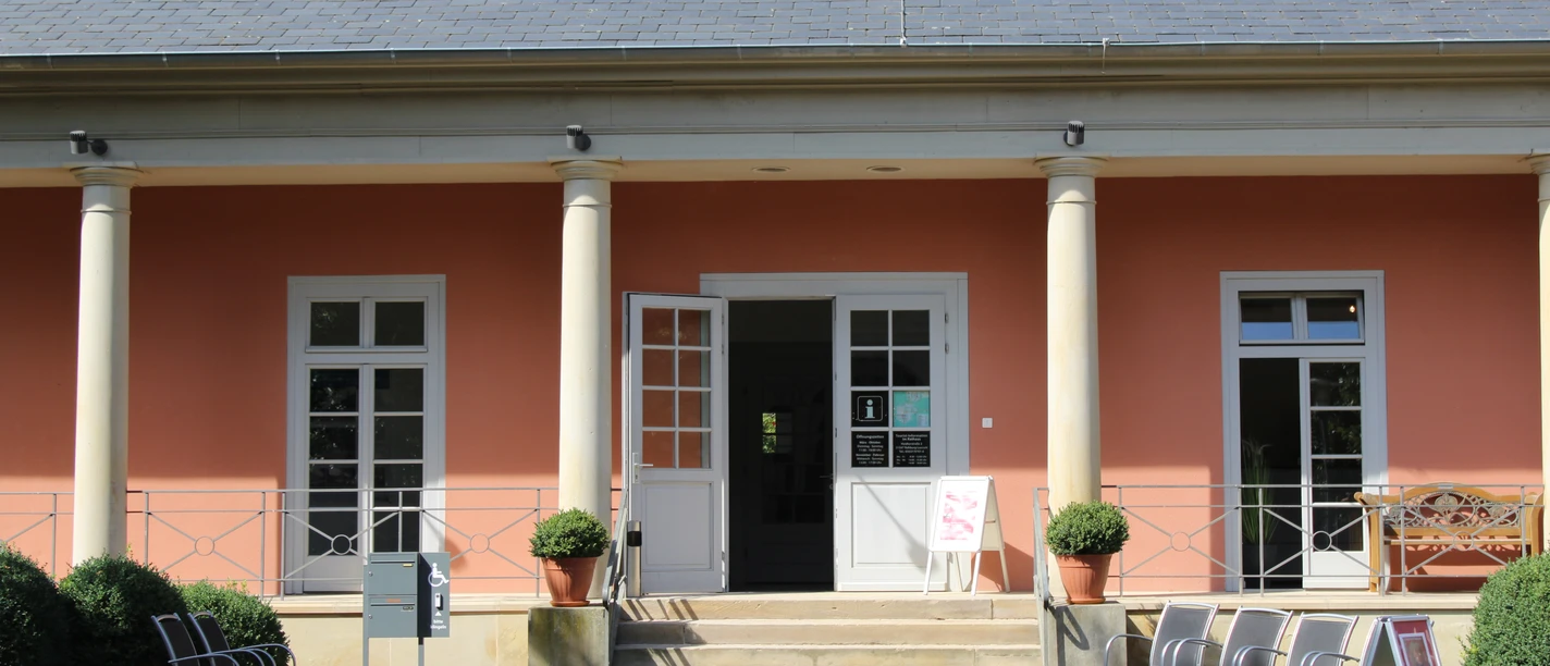 Romantik Bad Rehburg Geschichtsträchtiges Gebäude mit Säuleneingang, orangener Fassade und einladenden Stühlen draussen.