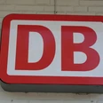 Rotes DB-Logo der Deutschen Bahn auf heller Ziegelwand montiert. Symbol für den Schienenverkehr.