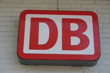 Deutsche Bahn Rotes DB-Logo der Deutschen Bahn auf heller Ziegelwand montiert. Symbol für den Schienenverkehr.