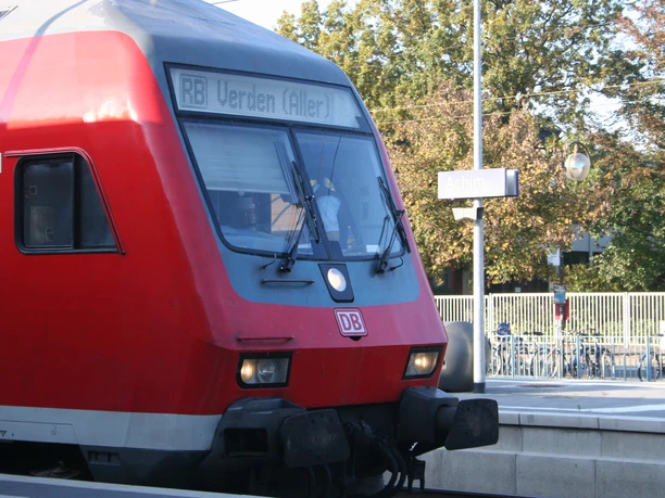 Bahnhof Achim Roter Regionalzug bei sonnigem Wetter am Bahnhof Achim mit klarem, hellblauem Himmel im Hintergrund.