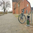 Die Fahrradreparaturstaion im Lügder Emmerauenpark Fahrrad steht an einer Reparaturstation im Emmerauenpark Lügde, neben einer gepflasterten Allee.