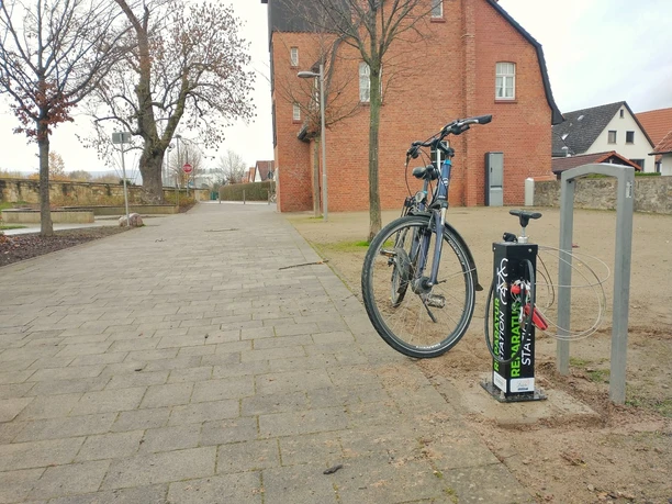 Die Fahrradreparaturstaion im Lügder Emmerauenpark Fahrrad steht an einer Reparaturstation im Emmerauenpark Lügde, neben einer gepflasterten Allee.