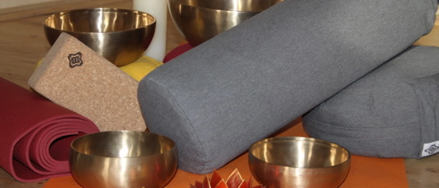 Yoga im Spiegelhaus Woltzeten Je ziet klankschalen, kussens, rollers, yogamatten en een kaars.