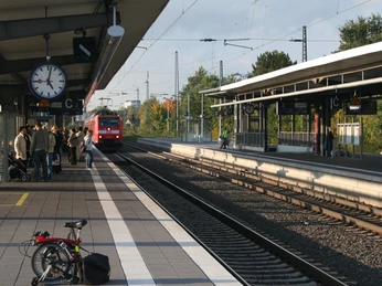 Menschen warten auf einem belebten Bahnsteig in Nienburg. Ein Zug nähert sich dem Bahnhof.