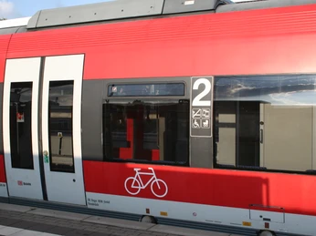 Regionalbahn Ein Regionalzug in leuchtendem Rot steht am Bahnsteig, bereit zur Weiterfahrt mit Fahrradbereich.