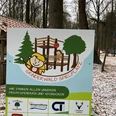 Grinderwald Spielplatz Ein verschneiter Spielplatz im Grinderwald, umgeben von Bäumen, mit Holzklettergerüst und Schaukeln.
