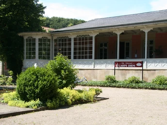 Romantik Bad Rehburg Historisches Gebäude mit verglaster Veranda hinter üppigem Garten; Restaurant Carpe Diem sichtbar.Historic building with glazed veranda behind lush garden; Carpe Diem restaurant visible.Historisk bygning med glasveranda bag frodig have; restaurant Carpe Diem er synlig.Historisch gebouw met glazen veranda achter weelderige tuin; restaurant Carpe Diem zichtbaar.