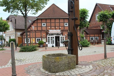 Ortsmitte Bruchhausen-Vilsen Historisches Fachwerkhaus mit Schriftzug "KAFFEEHAUS", umgeben von Pflastersteinen und Bäumen.