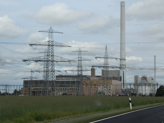 Landesbergen Kraftwerk Ein großes Kraftwerk mit hohen Schornsteinen und Strommasten vor bewölktem Himmel und Wiesen.
