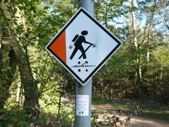 Wanderwegmarkierung im Waldgebiet mit Schild "Achimer Höhen" zur Orientierung für Wanderer.