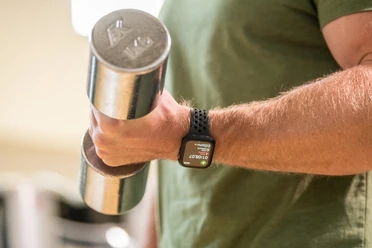 Trans World Hotel Kranichhöhe Nahaufnahme einer Hand mit einer Hantel, am Handgelenke eine Smartwatch