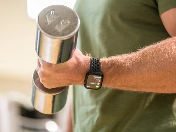 Trans World Hotel Kranichhöhe Nahaufnahme einer Hand mit einer Hantel, am Handgelenke eine Smartwatch