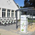 Bergisches E-Bike Fahrradverleihstation mit Schutzdach, mehreren Fahrrädern und Bedienungssäule auf gepflastertem Boden.