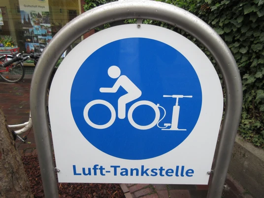 Ein Schild mit blauem Kreis und Piktogramm einer Person auf einem Fahrrad. Schrift: Luft-Tankstelle.