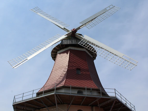 Thedinghausen Windmühle Emtinghausen Thedinghausen Windmühle Emtinghausen mit roten Ziegeln und weißen Flügeln vor blauem Himmel.