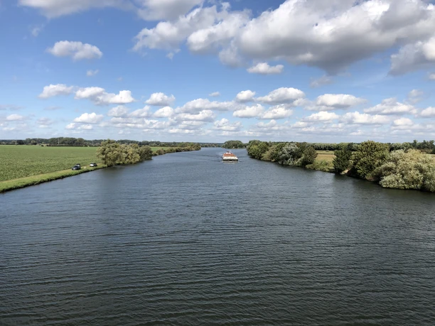 Weser, Landesbergen Die Weser fließt unter einem Himmel mit weißen Wolken durch eine grüne Landschaft bei Landesbergen.