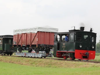 Historische Museums-Eisenbahn mit roten Flachwagen auf grüner Landschaft bei Bruchhausen-Vilsen.