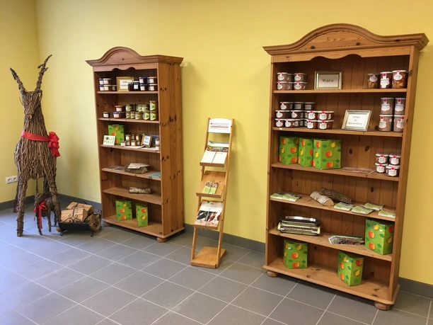 Verschiedene Prdoukte Zwei Holzregale mit Gläsern, Säften und lokalen Produkten sowie Deko-Rehe aus Korbgeflecht.